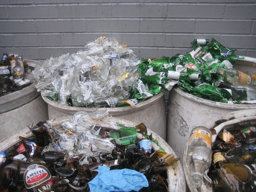 Multiple coloured glass beer bottles in bins. 